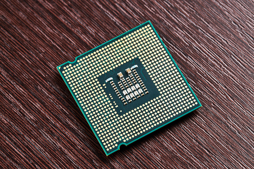cpu processor hardware unit over wooden background. computer chip close up. digital industry concept.