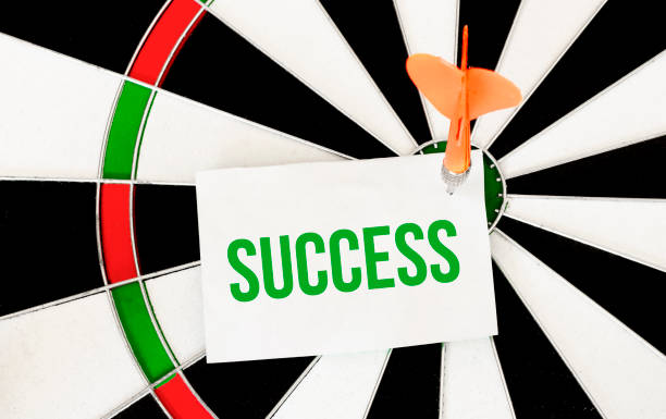 istock Handwriting SUCCESS on notepaper with dart arrow and dart board. 1267018676