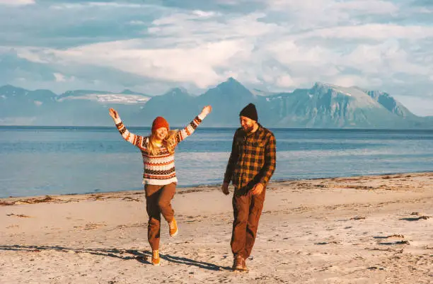Photo of Happy couple traveling together joyful walk on beach in Norway man and woman lifestyle  summer vacations outdoor