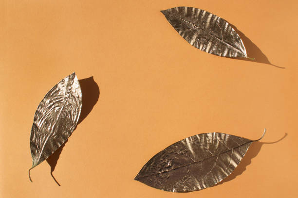 istock Leaves painted in gold on an orange background. 1267024698