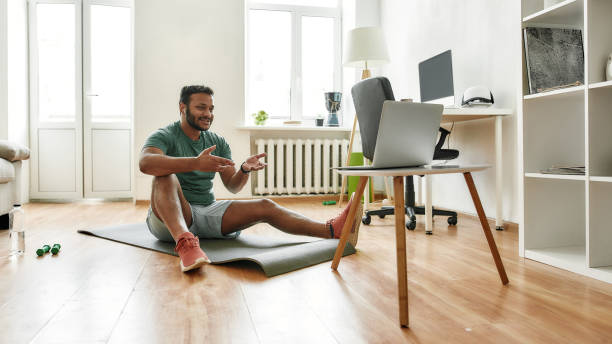 istock Motivate. Male fitness instructor explaining exercises while streaming, broadcasting video lesson on training at home using laptop. Sport, online gym concept 1267026787