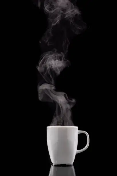 Coffee cup and steam. Freshly brewed coffee in a white ceramic mug. Dark background.