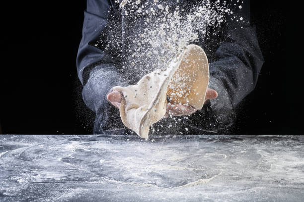 Chef throwing dough for pizza on dark backrground stock photo
