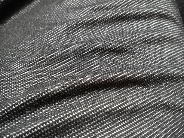 istock Textile fabric made on a loom by weaving mutually perpendicular yarns. Gray synthetic fabric for sewing clothes, upholstery and other products. Material close-up. Crumpled waves on the fabric 1267035688