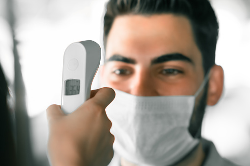 Measuring temperature of a young man with face mask at restaurant
