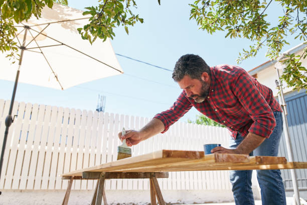 istock Construction carpenter using lacquering wooden planks outdoors 1267039148