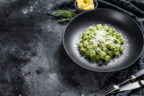 istock Gnocchi with basil spinach sauce and Parmesan. Italian potato paste. Black background. Top view. Copy space 1267039842