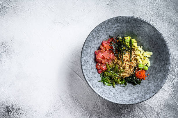 Tuna poke bowl with seaweed, avocado, cucumber, radish, sesame seeds. Gray background. Top view. Copy space