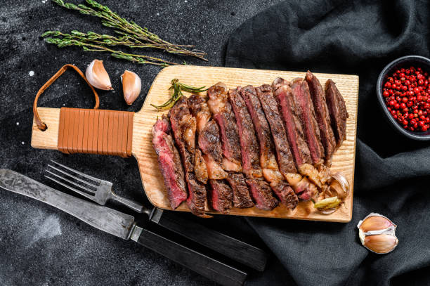 istock Sliced rib eye steak on a chopping Board, medium rare. black background. top view. Copy space 1267041648