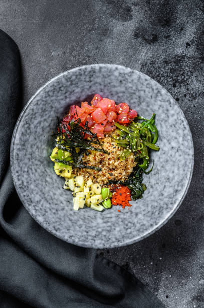 Poke bowl with raw tuna fish and vegetables. Hawaiian dish. Healthy eating concept. Black background. Top view