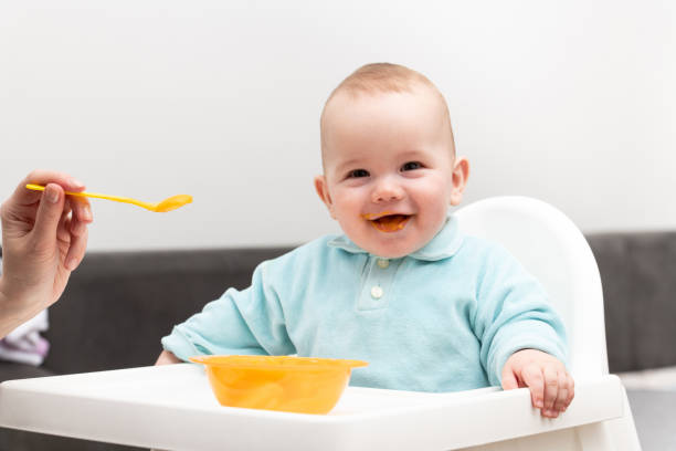 istock Mom Feeds Baby With Fruit Puree At Home 1267043315