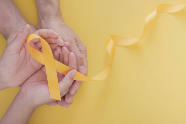 adult and child hands holding yellow gold ribbon, Sarcoma Awareness, Bone cancer, childhood cancer awareness, world suicide prevention day, September Yellow adult and child hands holding yellow gold ribbon, Sarcoma Awareness, Bone cancer, childhood cancer awareness, world suicide prevention day, September Yellow september stock pictures, royalty-free photos & images
