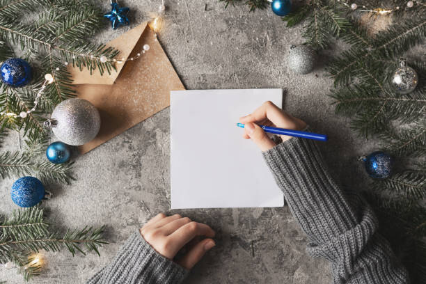 Top view of blank notebook on white wooden background with xmas decorations, copy space. Christmas background with notebook for wish list or to do list, red gift boxes, fir tree branches. Flat lay