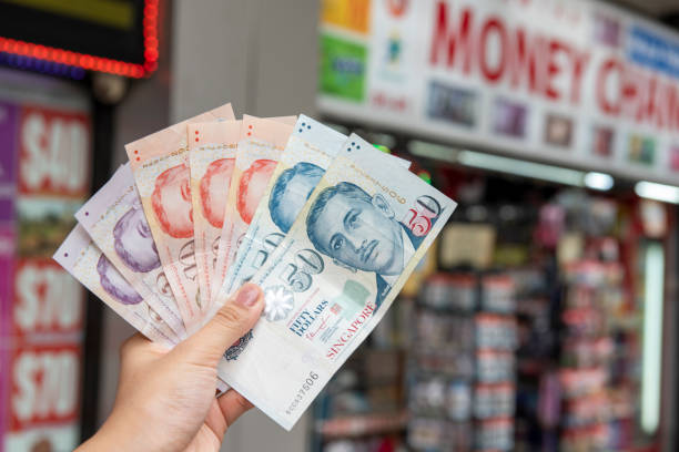 Hand holding Singapore dollar banknotes Hand holding Singapore dollar banknotes, currency exchange concept singapore cash stock pictures, royalty-free photos & images