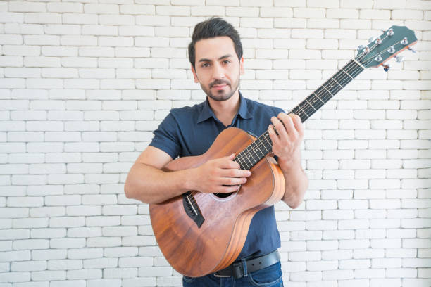 happy man playing guitar while sitting on sofa in living room, enjoying carefree time at home. - 16707 imagens e fotografias de stock