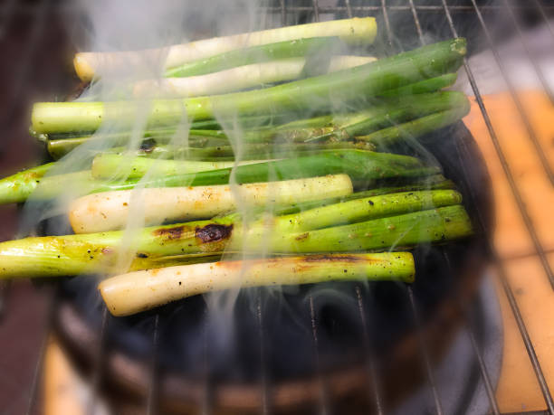 green onion or chives, with olive oil, and ingredients, roasted on a home grill, smoke comes out of the cooking, delicious flavor. - fine dining grilled spring onion healthy lifestyle imagens e fotografias de stock