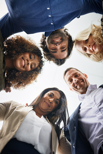 Shot of a group of businesspeople huddled together in solidarity in a modern office