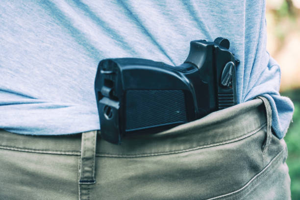 la pistola è nascosta dietro la schiena dell'uomo - hiding carrying weapon handgun foto e immagini stock