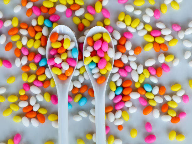 Multi colored fennel sugar candy in spoons and scattered as background Multi colored fennel sugar candy in spoons and scattered as background, texture dissert stock pictures, royalty-free photos & images