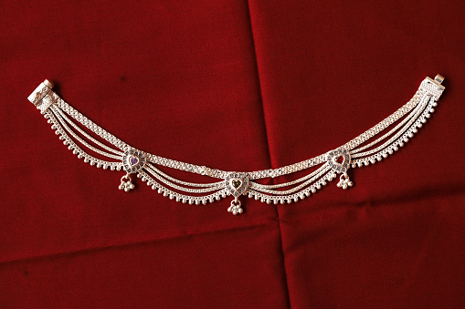Indian Silver Anklets Jewellery Isolated On Red Background.