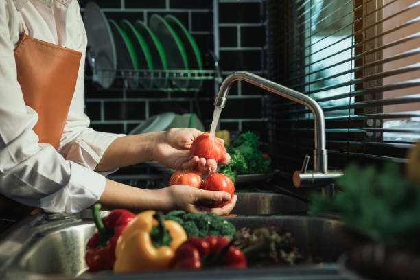 アジアの手の女性は野菜トマトを洗い、台所で健康的な食べ物を準備します。 - cleaning domestic kitchen clean chef ストックフォトと画像