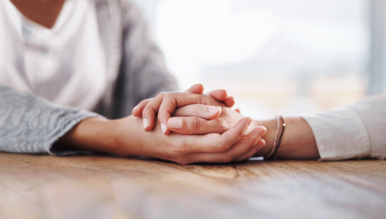 Closeup shot of two unrecognisable people holding hands in comfort