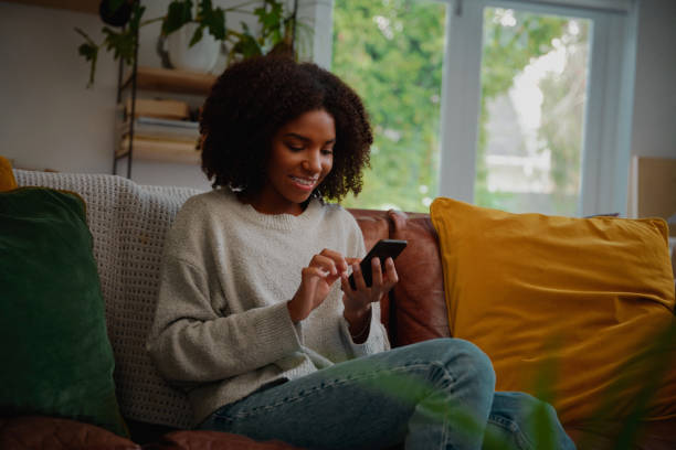 istock Smiling girl relaxing at home using cellphone for texting and chatting with friends 1267081325