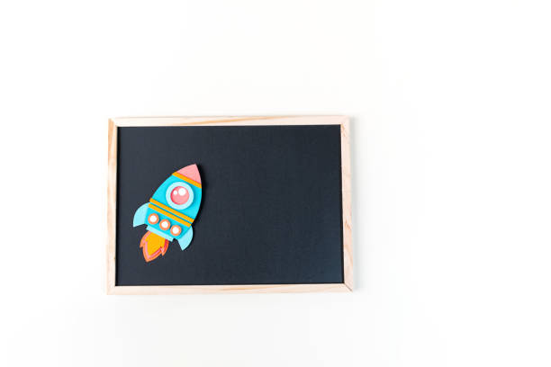 istock Rocket paper craft. Back to school education. Black chalkboard background 1267083782