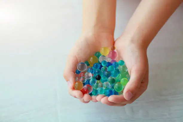 Children is hands are holding the orbeez. Decoration with hydrogel water balls - orbeez. Copy space