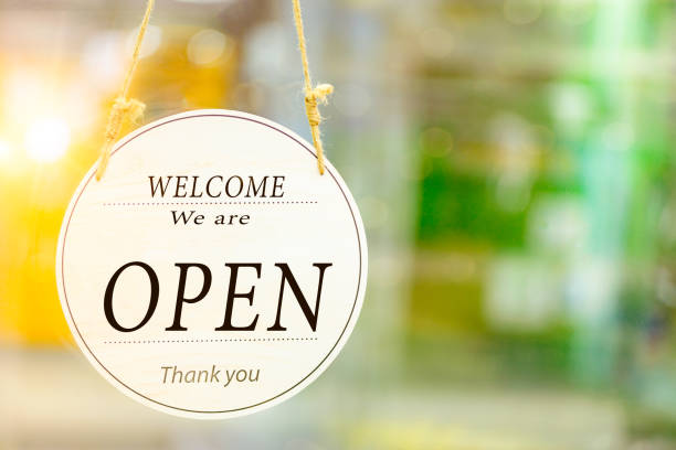 Text on the white signboard "we're open" in front of the glass's shop with the bokeh yellow and green bright background. stock photo