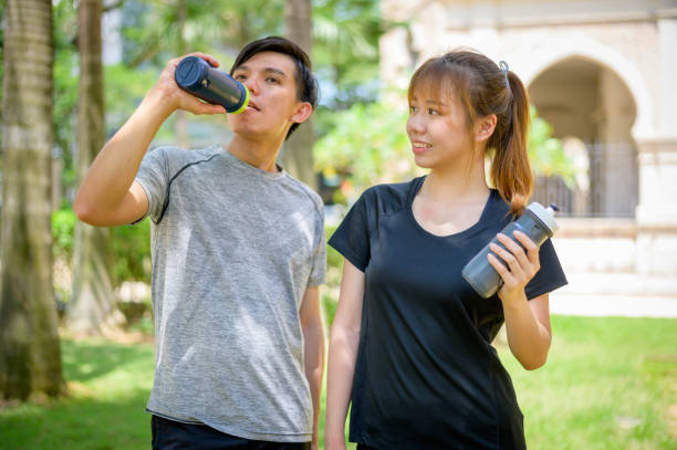 istock Athletic young Asian couple drinking water after running 1267085931