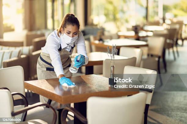 Camarera Con Mascarilla Facial Y Guantes Mesas De Limpieza Con Desinfectante En Una Cafetería Foto de stock y más banco de imágenes de Restaurante