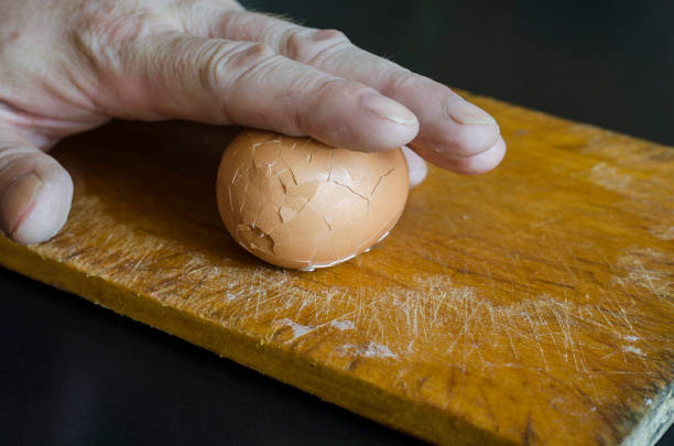 istock A mature male hand holds a boiled chicken egg in its shell against the chopping board. 1267087307
