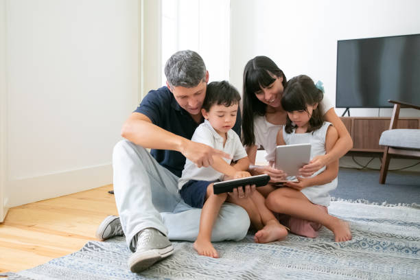istock Caucasian mom and dad hugging children, using tablets and phone 1267089529
