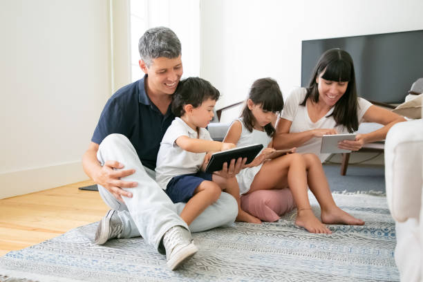 istock Young parents and cute kids using mobile devices on floor 1267091501