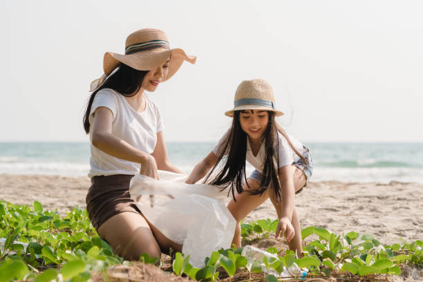 jovens ativistas da família asiática felizes coletando resíduos plásticos na praia. - mulher catando lixo - fotografias e filmes do acervo