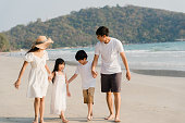 アジアの若い幸せな家族は夕方にビーチで休暇を楽しんでいます。