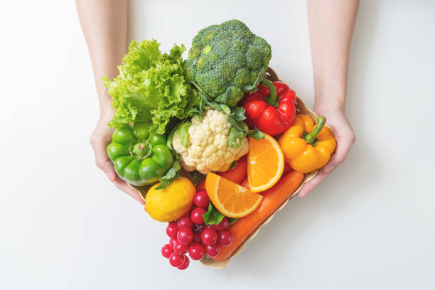 крупным планом руки женщина со свежими овощами в коробке. вид сверху - basket of fruits стоковые фото и изображения