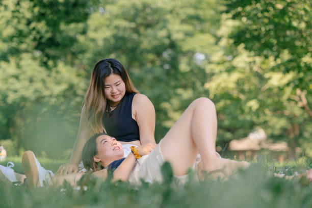 istock Two female friends enjoying talking with each other while relaxing in outdoors in public park 1267102396