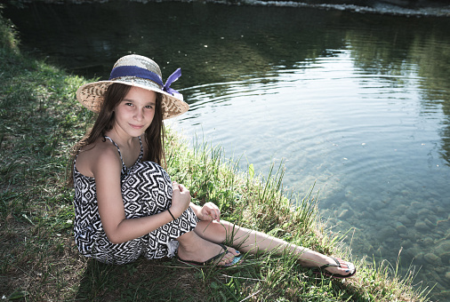 Portrait of beautiful girl in hat sitting by the river Zrmanja, Croatia