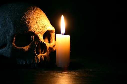 Vintage still life with lighting candle near human skull