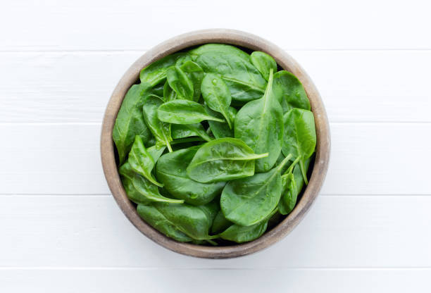 istock Spinach in a bowl on a white wooden background 1267104924