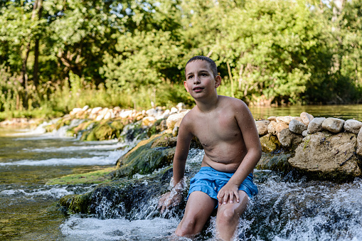 The boy is sitting on a small waterfall on the river Zrmanja, Croatia