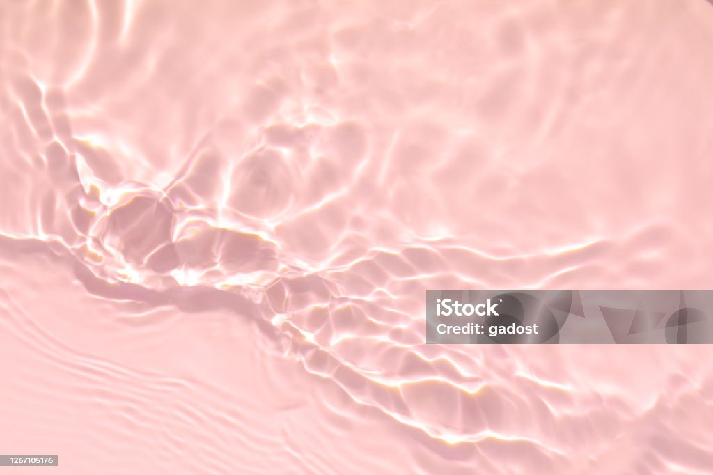 pink transparent clear water surface texture summer background Closeup of pink transparent clear calm water surface texture with splashes and bubbles. Trendy abstract summer nature background. Coral colored waves in sunlight. Water Stock Photo