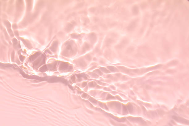pink transparent clear water surface texture summer background Closeup of pink transparent clear calm water surface texture with splashes and bubbles. Trendy abstract summer nature background. Coral colored waves in sunlight. skin care photos stock pictures, royalty-free photos & images