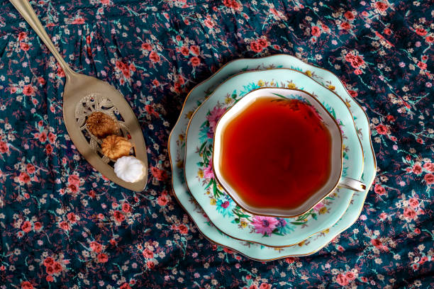 istock Still life with a vintage cup of tea and silver spoon with sugar on a flowers pattern background 1267106913