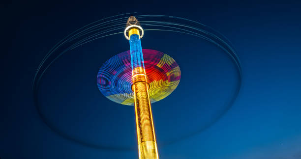 traces colorées abstraites de carrousel devant le ciel foncé - blurred motion amusement park spinning lighting equipment photos et images de collection