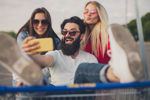 istock Young friends taking selfie in shopping trolley 1267112728