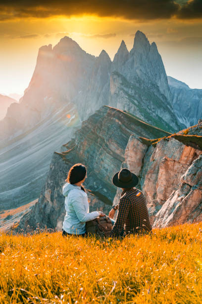 Couple sitting in a meadow and watching the sunset