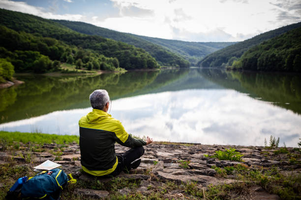 Mature man doing meditation by the lake